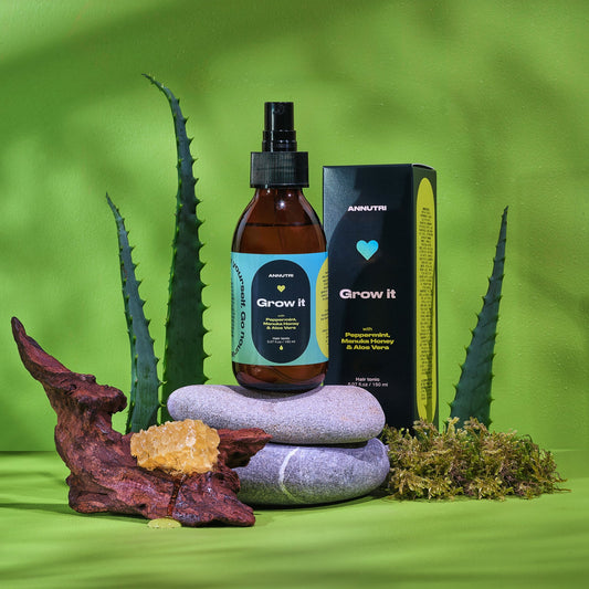 Bottle labeled 'Grow It' with packaging on stones against a green background