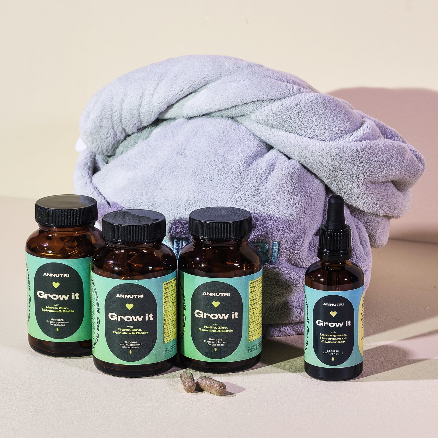 Four bottles and a dropper labeled 'Grow It' with a towel on a beige background