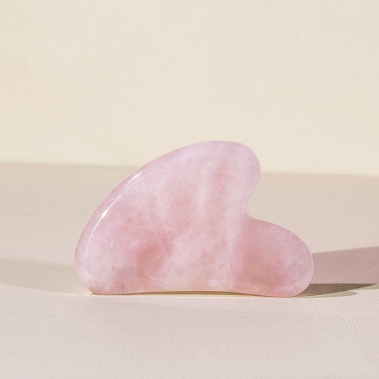 Rose Quartz Gua Sha Stone For Facial Massage on a beige background