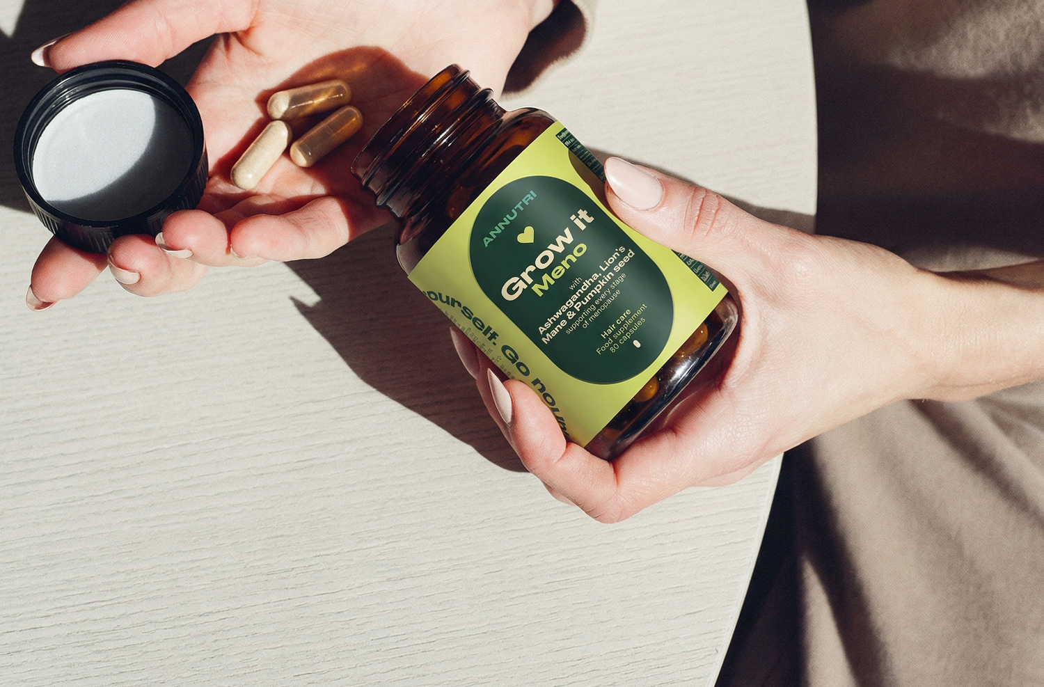 Person holding a bottle labeled 'Grow It' with capsules and a black container.