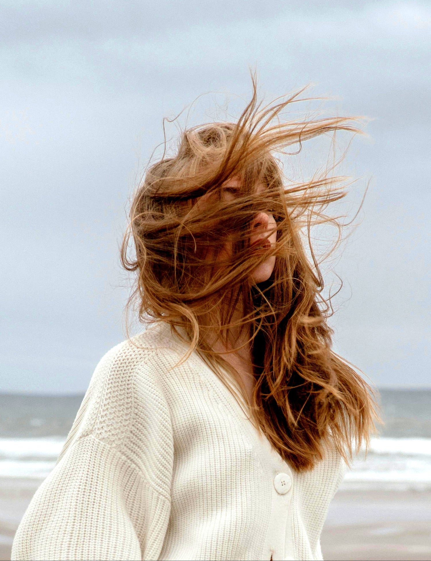Person with long hair blowing in the wind on a beach